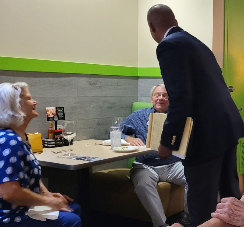 Victor Arias speaking with a senior couple about healthcare concerns at a local restaurant